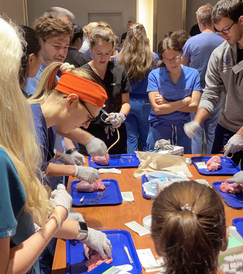 A group of simulation students studies anatomy.