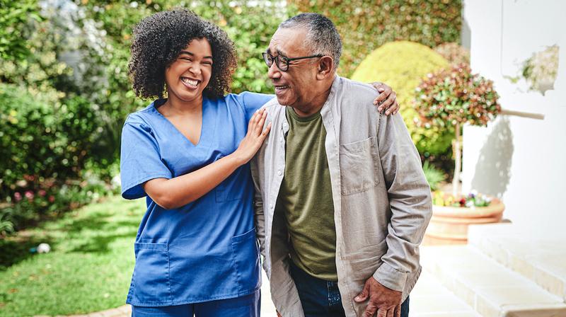 A young home care nurse walks with an elderly patient.