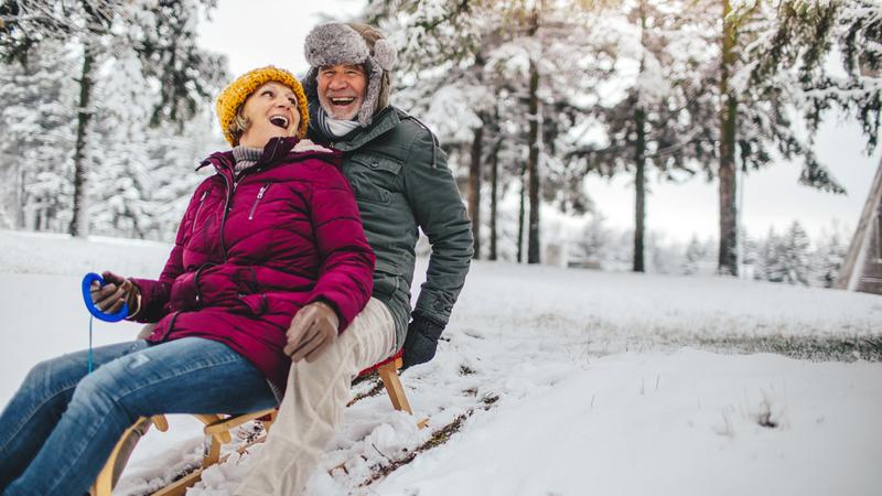 Photo of a lovely, elderly couple who still enjoy sledding as when they were kids