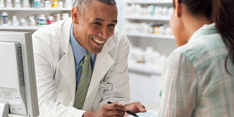 A pharmacist talks with a patient in a pharmacy setting.