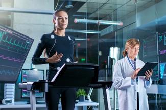 A female athlete runs on a treadmill while wearing electrodes and being monitored by a doctor.