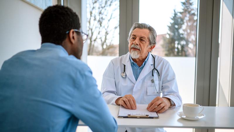 An experienced doctor talks with a patient in an office setting.