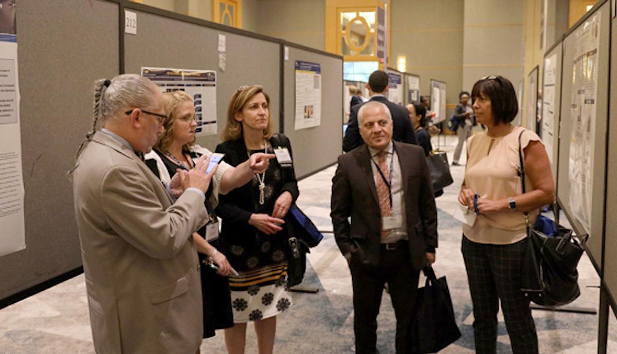 A group of medical professionals looks at a display of abstracts at a medical symposium event.