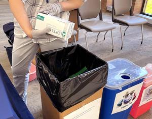 Two MedStar pharmacists wearing masks work at an event to take back unused drugs and pharmaceutical paraphenalia for safe disposal.