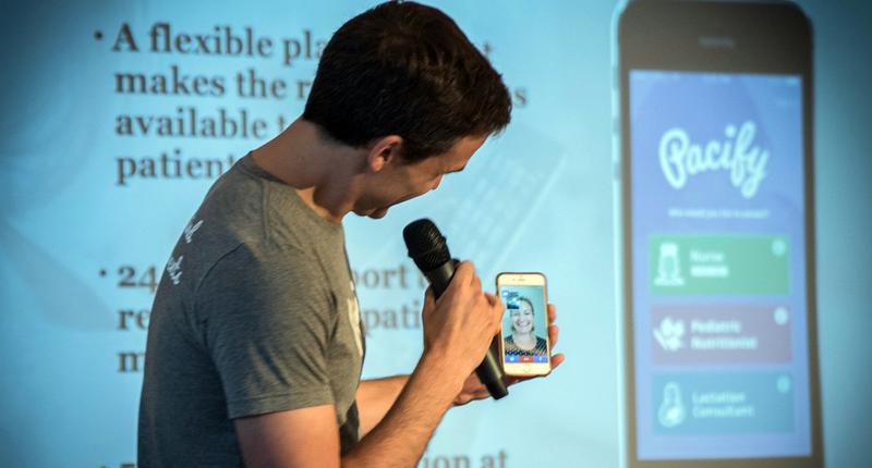 A speaker on a stage holds a cell phone while speaking.