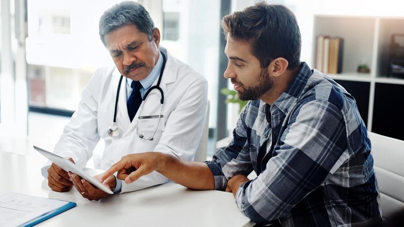 A doctor consults with a male patient in a clinical setting.