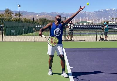 Tennis star Frances Tiafoe serves the ball during a practice session outdoors.