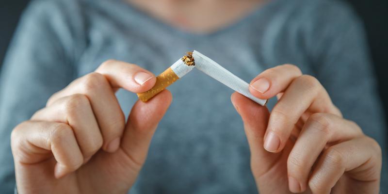 Close-up view of a person breaking a cigarette in half because they are participating in tobacco cessation treatment classes.