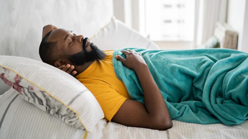 A man lays sleeping in his bed.