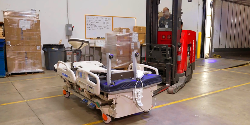 A worker driving a red forklift, loads a hospital bed into a trailer for transport. MedStar Health partnered humanitarian organizations to donate hospital beds, surgical instruments, personal protective equipment, and other medical supplies.