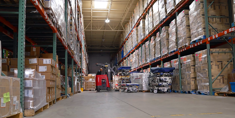 A worker driving a red forklift, inside of a large medical supply warehouse. MedStar Health partnered humanitarian organizations to donate hospital beds, surgical instruments, personal protective equipment, and other medical supplies.