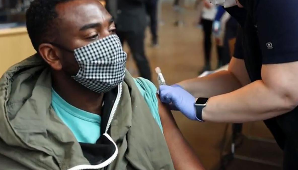Close-up of a nurse giving a patient wearing a mask a COVID-19 vaccine shot