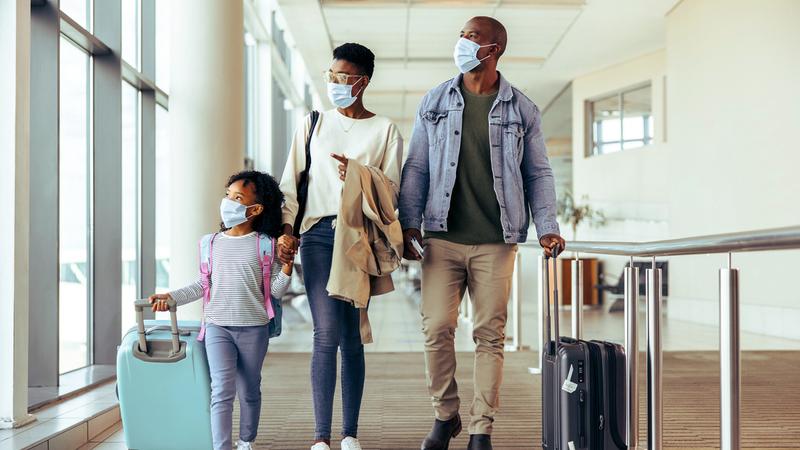 Tourist family walking through passageway in airport