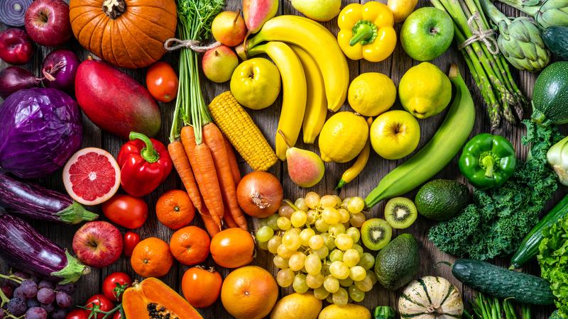 A rainbow of fresh fruits and vegetables is displayed on a table.