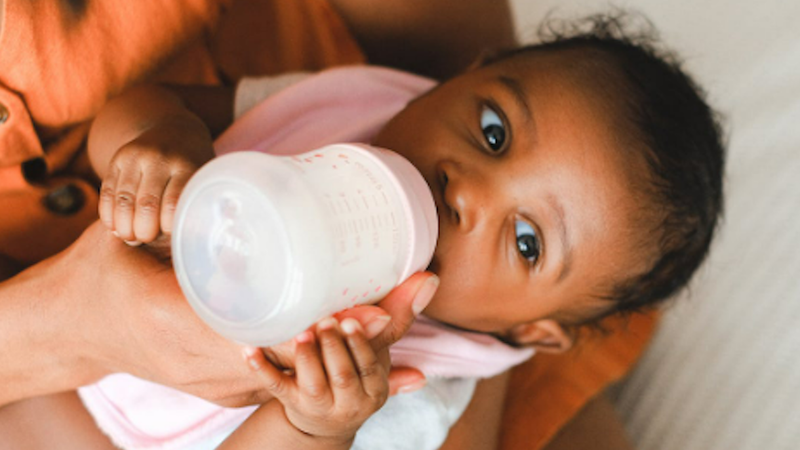 A mother feeds her infant a bottle.