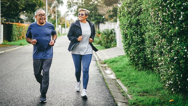A mature couple enjoys a run on a suburban street.