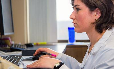 A medical professional works at a computer.