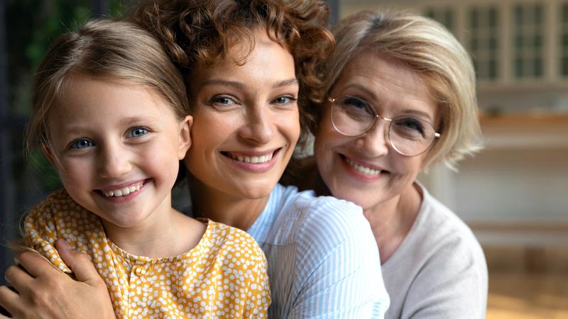 三个女人，一个女孩，母亲和祖母，在她们的家里摆姿势拍照。
