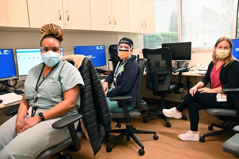 Staff of the new Women's Care center at MedStar Washington Hospital Center turn from their desks to pose for a photo. Everyone is wearing a mask and PPE.