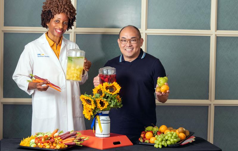 Photo of a doctor and another person holding fresh fruits and vegetables.
